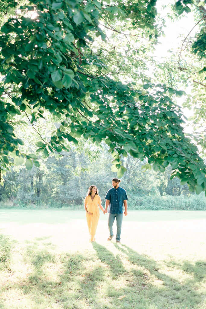 Bentonville maternity captures couple walking, mother has hand on her pregnant belly. 