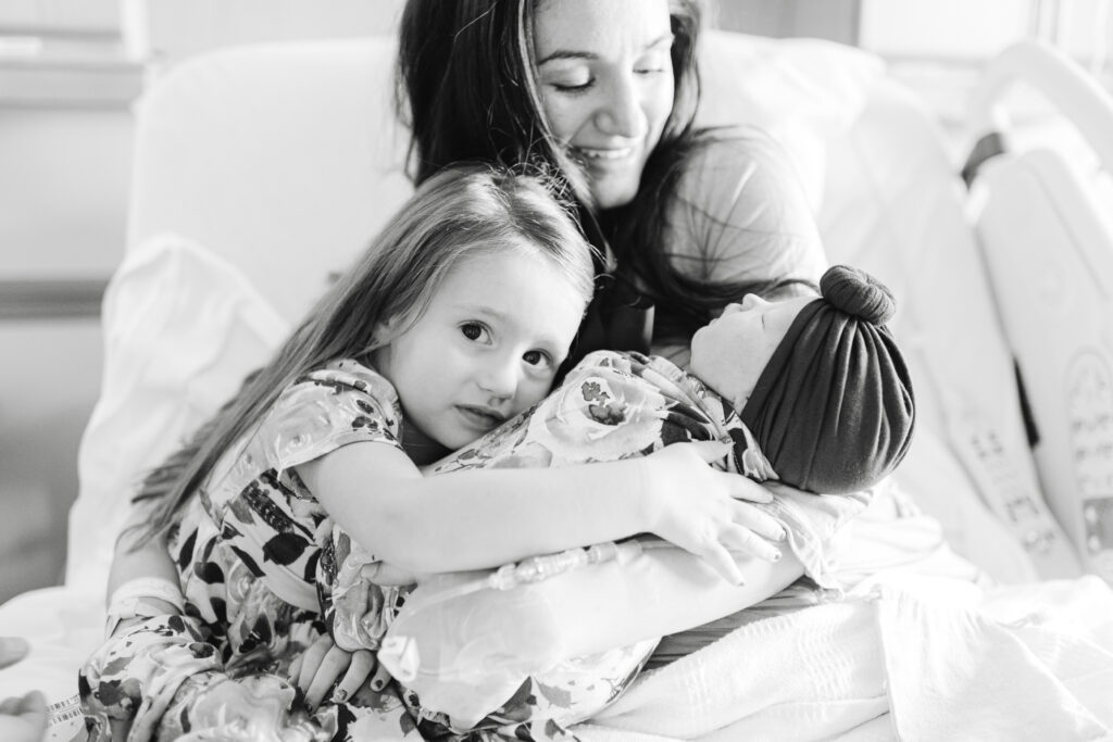 Big sister hugging her new baby sister, radiating love and joy at Northwest Medical Center Bentonville