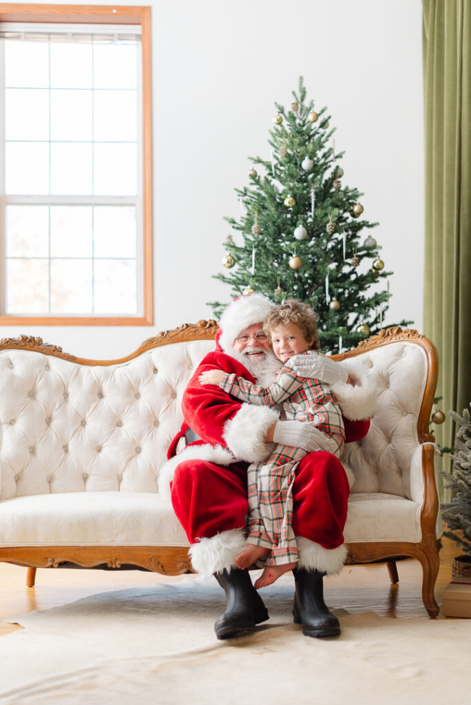 A little boy smiling for pictures with Santa. 