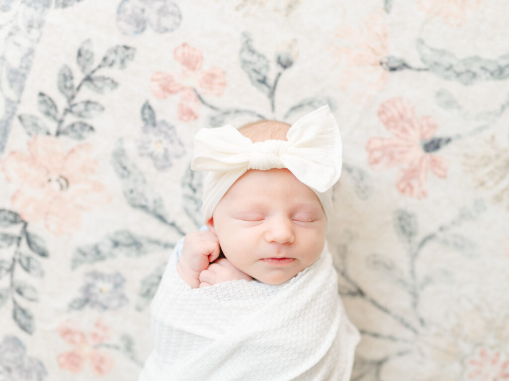 Swaddled newborn lying on a neutral-colored rug, demonstrating how to use simple backgrounds for phone photography.