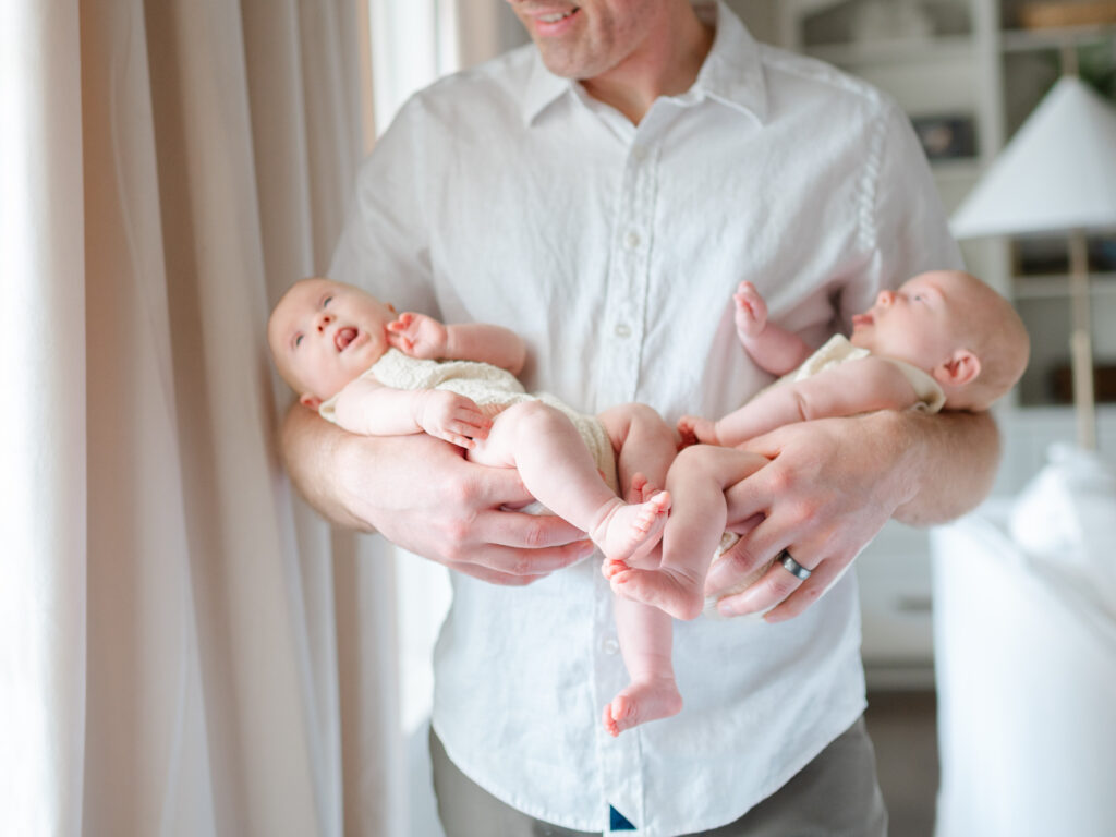 father holding twin newborns during in-home photography