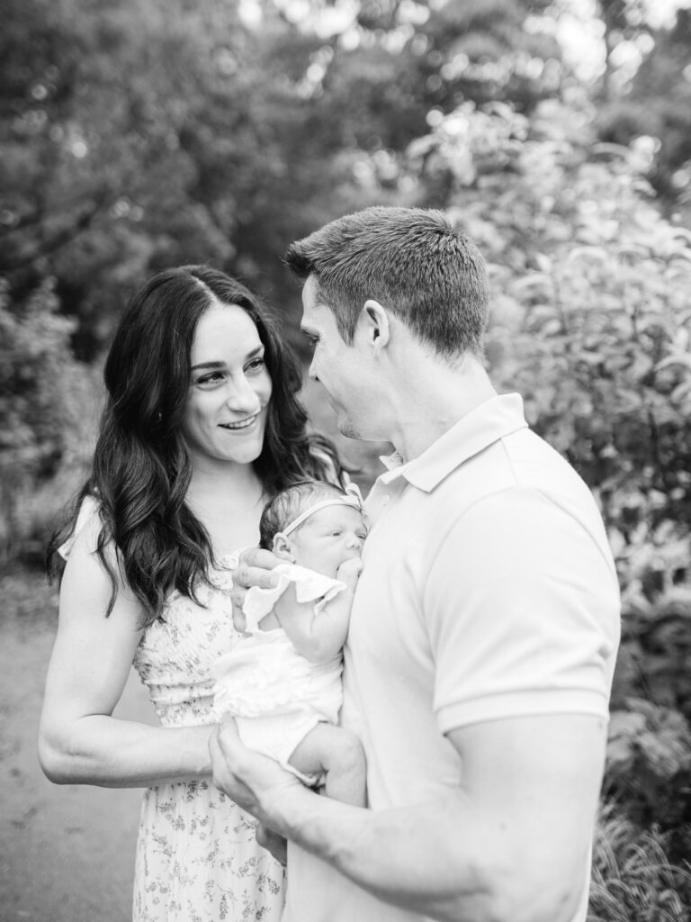 A candid moment captured during an outdoor newborn session at the Botanical Garden of the Ozarks, featuring Jordyn Wieber Brooks and her family.