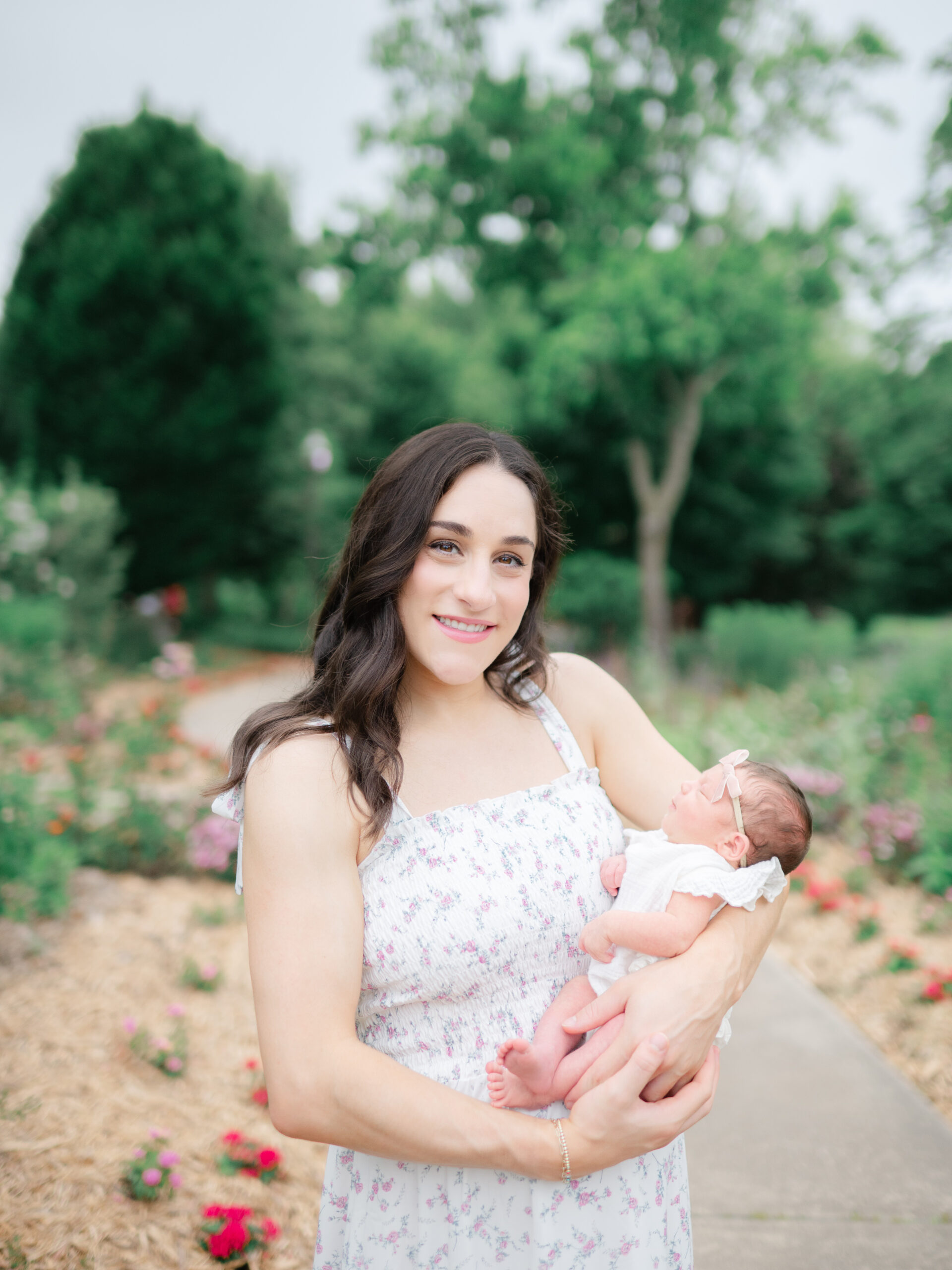 Jordyn Wieber Brooks holds her newborn daughter during a peaceful outdoor newborn session at the Botanical Garden of the Ozarks with Northwest Arkansas newborn photographer Leslie Nice.