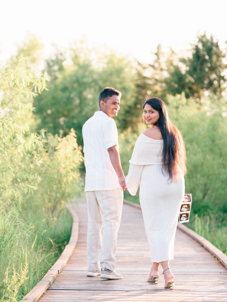 Couple walking hand-in-hand along the boardwalk at Osage Park during maternity photo session